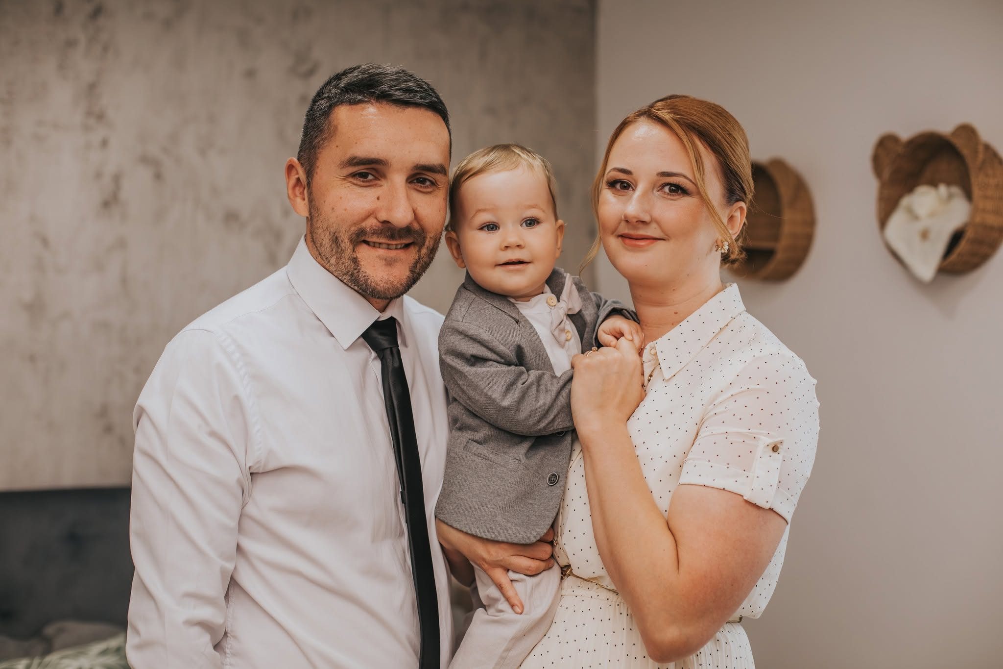 A szülők és a baba pillanatképe az ágyon, a keresztelő előtt