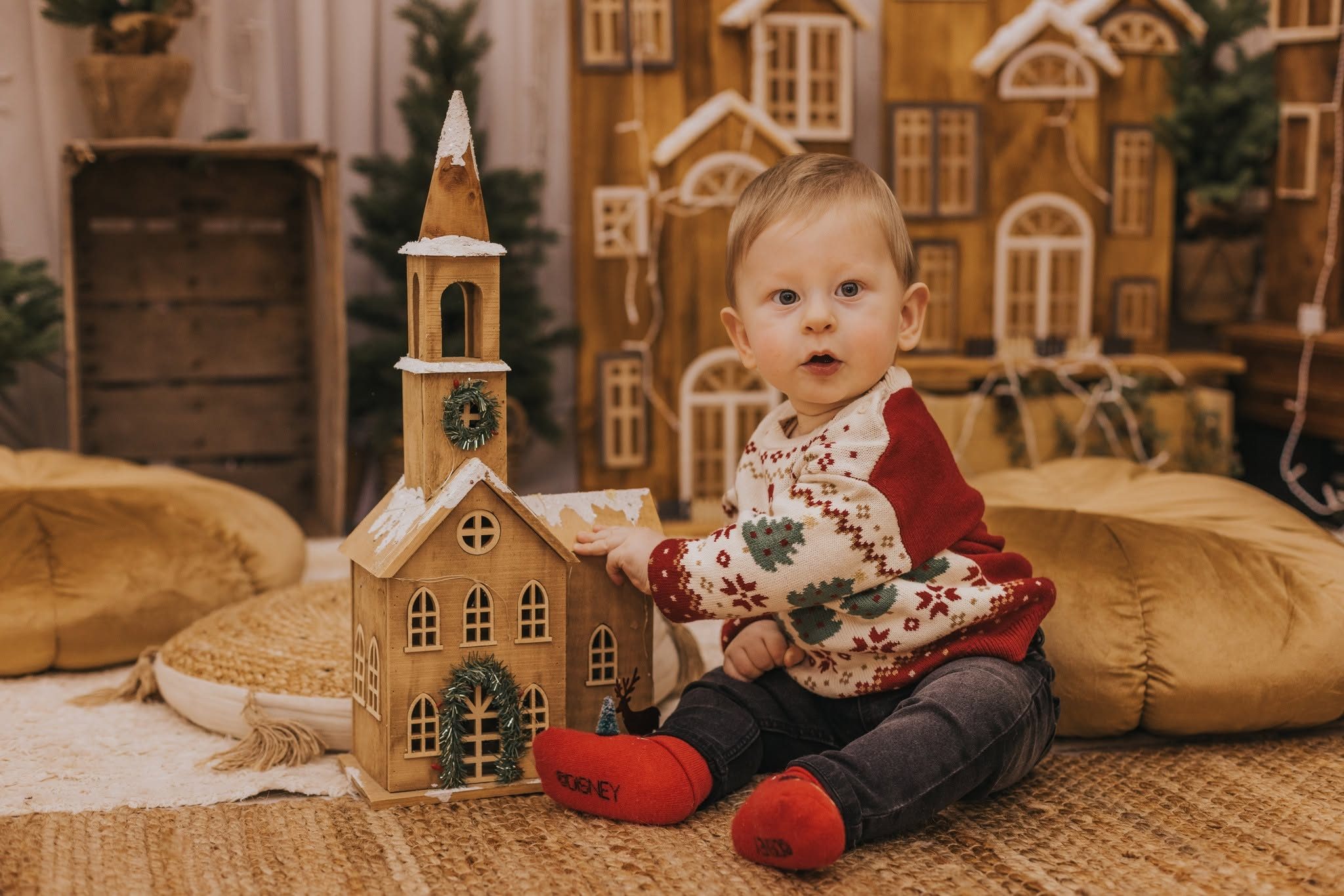 Gyerek a karácsonyi díszfalu makettje mellett ücsörög